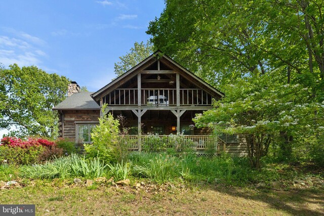 rear view of house featuring log exterior and a chimney