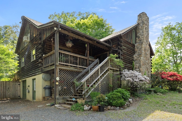 back of property featuring stairs, fence, a chimney, and log siding