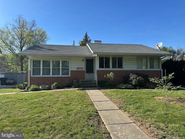single story home with roof with shingles, a front lawn, and brick siding