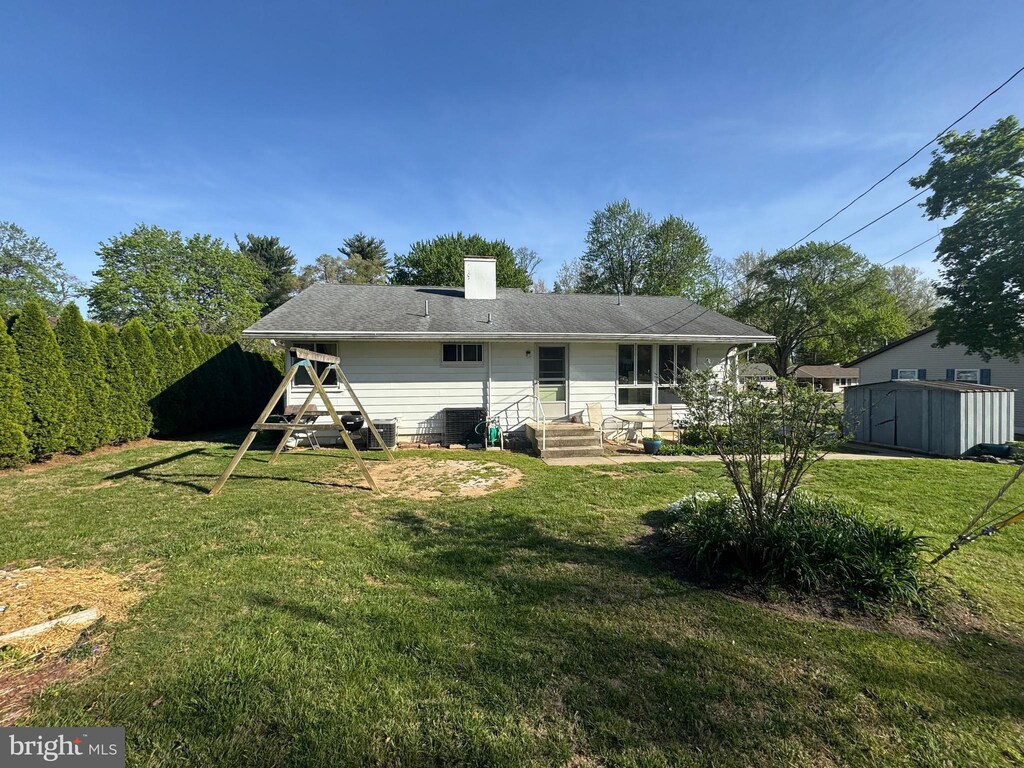 back of house with a lawn, a chimney, and entry steps