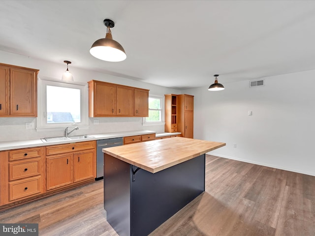kitchen featuring a sink, butcher block countertops, wood finished floors, stainless steel dishwasher, and pendant lighting