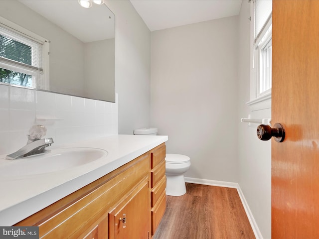 bathroom featuring toilet, baseboards, wood finished floors, and vanity