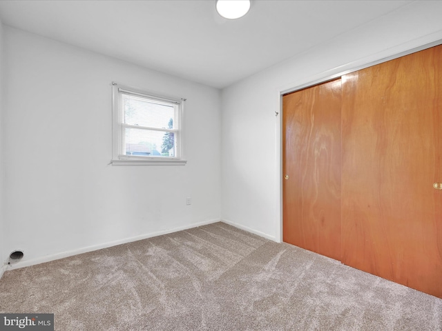 unfurnished bedroom with baseboards, carpet, and a closet