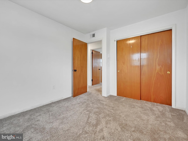 unfurnished bedroom featuring baseboards, visible vents, carpet, and a closet