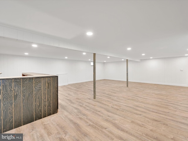 finished below grade area featuring bar and light wood finished floors