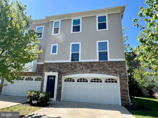 view of property with driveway, stone siding, and a garage