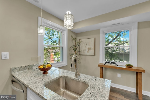 details with visible vents, light stone countertops, dishwasher, a sink, and baseboards