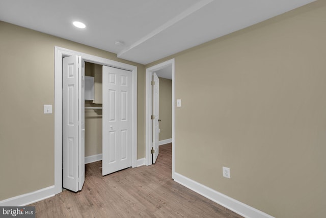 unfurnished bedroom featuring baseboards, a closet, recessed lighting, and wood finished floors