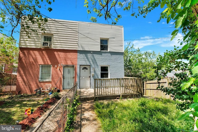 view of front of property featuring fence, a deck, and brick siding