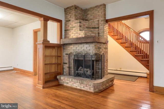 350 E Derry Rd, Hershey, PA 17033 - living area featuring baseboard heating, wood-type flooring, baseboards, a brick fireplace, and stairway