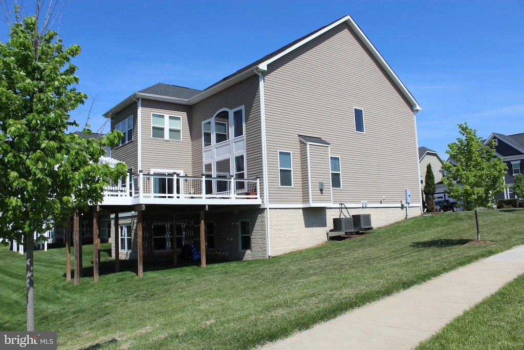 rear view of house with a lawn, central AC, and a deck