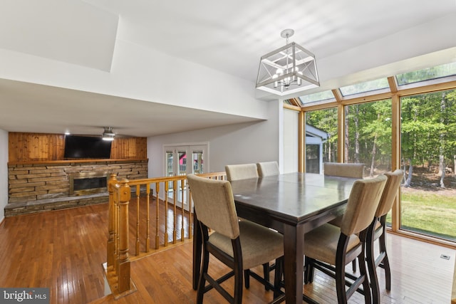 dining area featuring an inviting chandelier, a fireplace, and hardwood / wood-style flooring