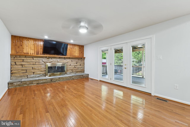 unfurnished living room featuring ceiling fan, light wood finished floors, a fireplace, baseboards, and visible vents
