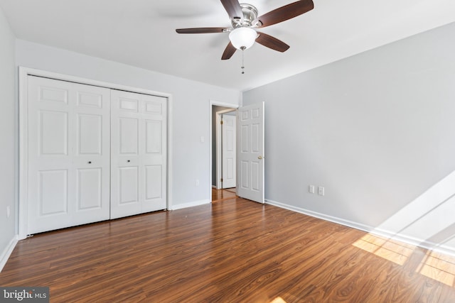unfurnished bedroom featuring baseboards, ceiling fan, a closet, and wood finished floors