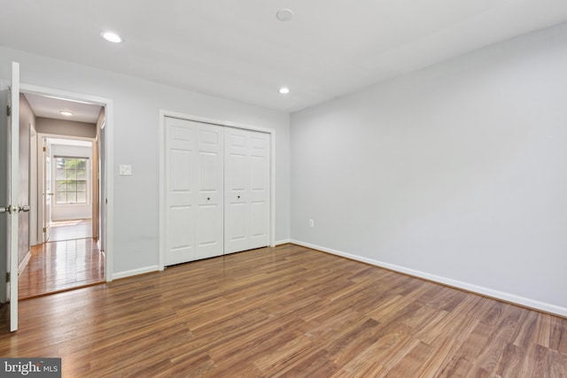 unfurnished bedroom featuring recessed lighting, baseboards, wood finished floors, and a closet