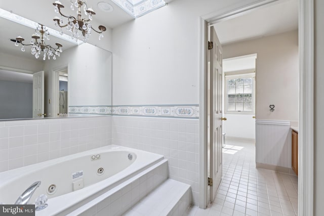 bathroom featuring a wainscoted wall, tile patterned flooring, a whirlpool tub, and a chandelier