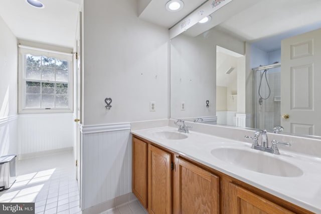 full bath featuring a sink, wainscoting, an enclosed shower, and double vanity