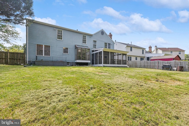 rear view of house featuring a sunroom, a fenced backyard, and a yard