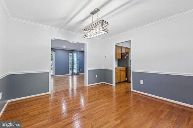 unfurnished dining area featuring baseboards, a notable chandelier, ornamental molding, and light wood-style flooring