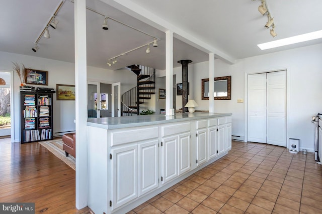 kitchen featuring baseboard heating, rail lighting, light countertops, a baseboard heating unit, and white cabinetry