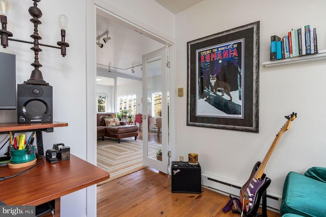 interior space featuring french doors, track lighting, a baseboard heating unit, and wood finished floors