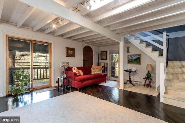 living area with arched walkways, stairway, hardwood / wood-style floors, and beamed ceiling