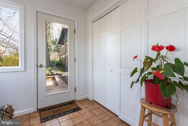 doorway featuring baseboards and light tile patterned floors