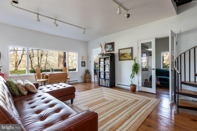 living room with track lighting, baseboard heating, stairs, and wood finished floors