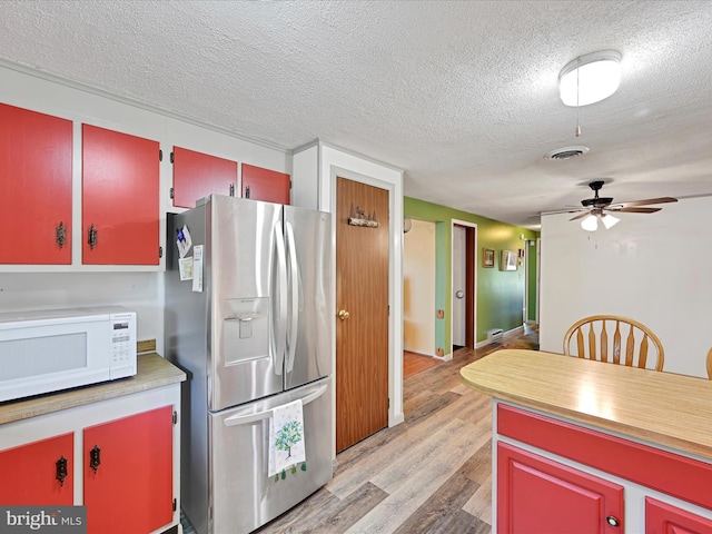 917 Houtztown Rd, Myerstown, PA 17067 - kitchen with red cabinets, a textured ceiling, white microwave, and stainless steel fridge with ice dispenser