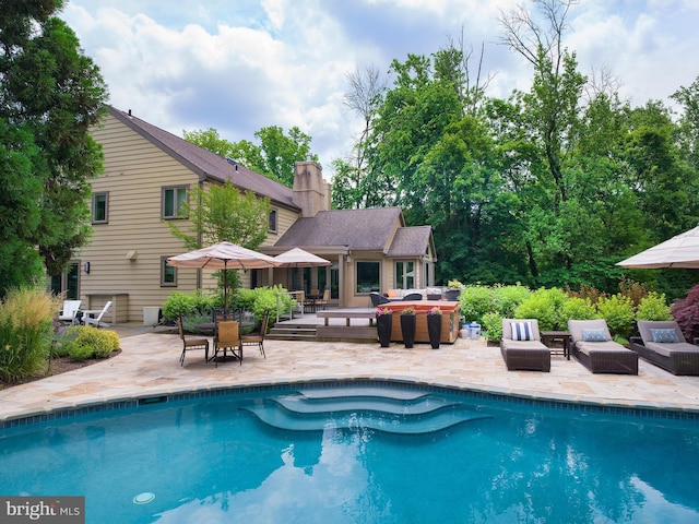 pool with an outdoor living space and a patio