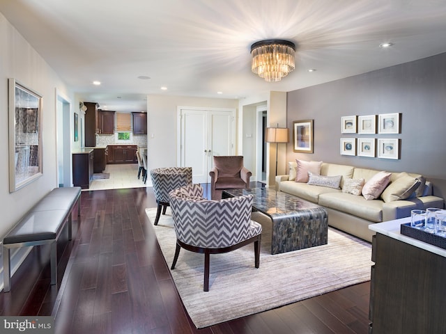 living room with recessed lighting, a notable chandelier, and dark wood-type flooring