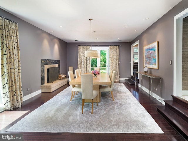 dining room featuring baseboards, dark wood-type flooring, recessed lighting, and a premium fireplace