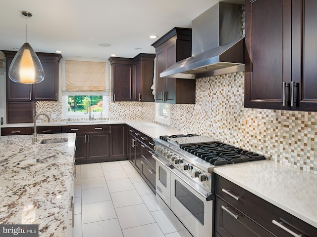 kitchen featuring wall chimney range hood, light tile patterned floors, double oven range, and a sink