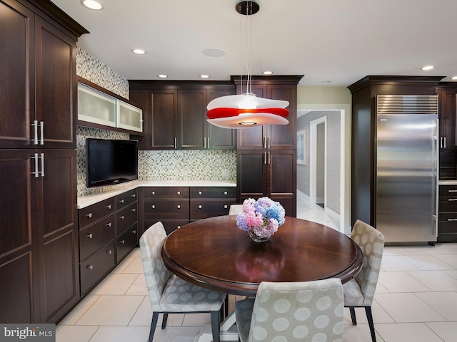kitchen with decorative backsplash, dark brown cabinetry, stainless steel built in fridge, light countertops, and light tile patterned floors
