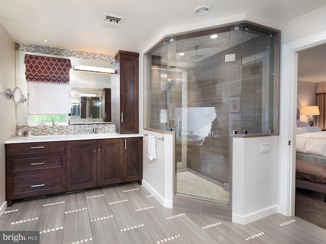 ensuite bathroom featuring connected bathroom, vanity, baseboards, a shower stall, and visible vents
