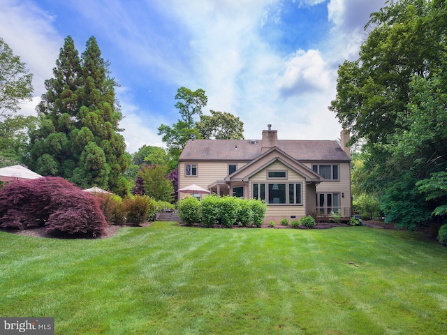 rear view of property with a lawn and a chimney