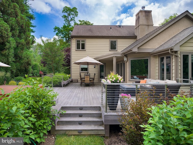 rear view of house with outdoor lounge area, a deck, roof with shingles, a chimney, and outdoor dining space