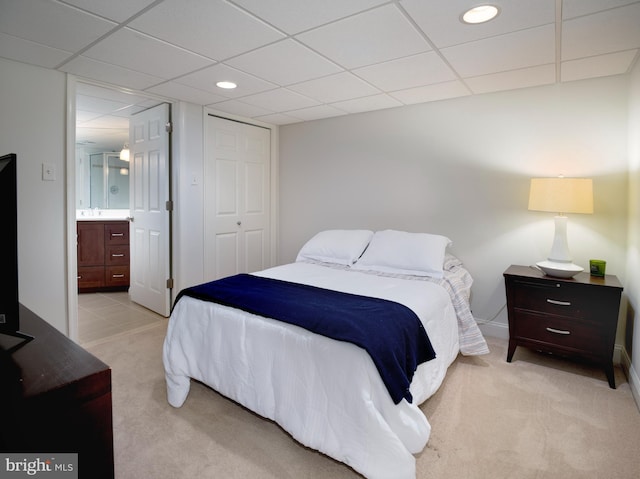 bedroom featuring connected bathroom, light carpet, recessed lighting, a drop ceiling, and a closet