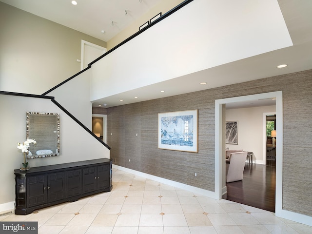 interior space with baseboards, recessed lighting, an accent wall, and wallpapered walls