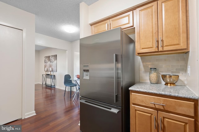 kitchen with stainless steel fridge with ice dispenser, a textured ceiling, dark wood finished floors, baseboards, and decorative backsplash