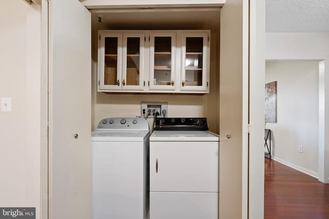 laundry area with cabinet space, separate washer and dryer, baseboards, and dark wood-type flooring