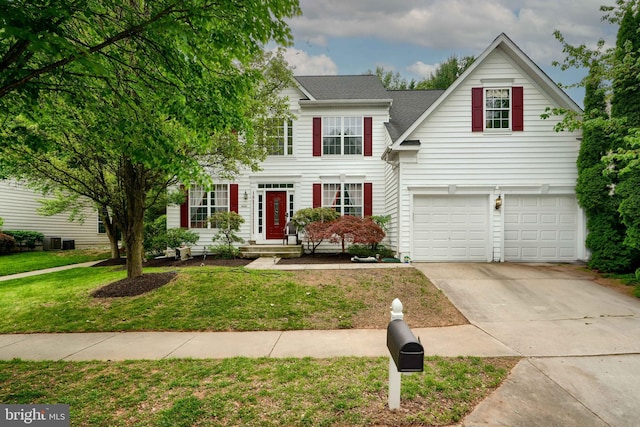 view of front facade with an attached garage, concrete driveway, a front yard, central AC, and a shingled roof