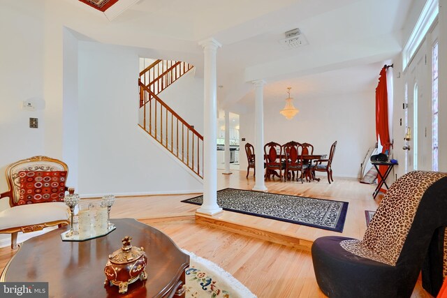 living room with ornate columns, wood finished floors, and stairs