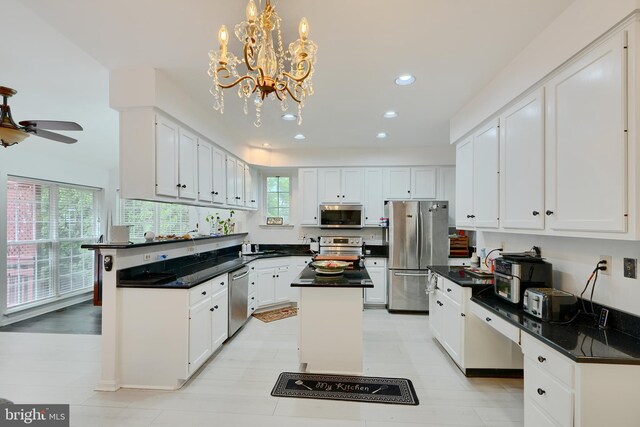 kitchen featuring stainless steel appliances, white cabinets, recessed lighting, a chandelier, and a center island