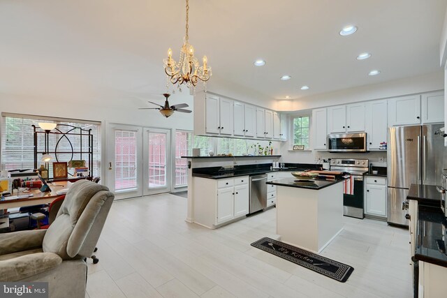 kitchen with stainless steel appliances, open floor plan, dark countertops, recessed lighting, and a chandelier