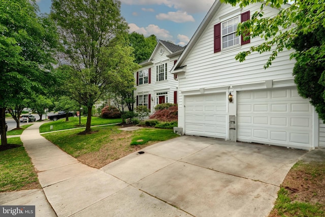 view of front of house featuring an attached garage, concrete driveway, and a front lawn
