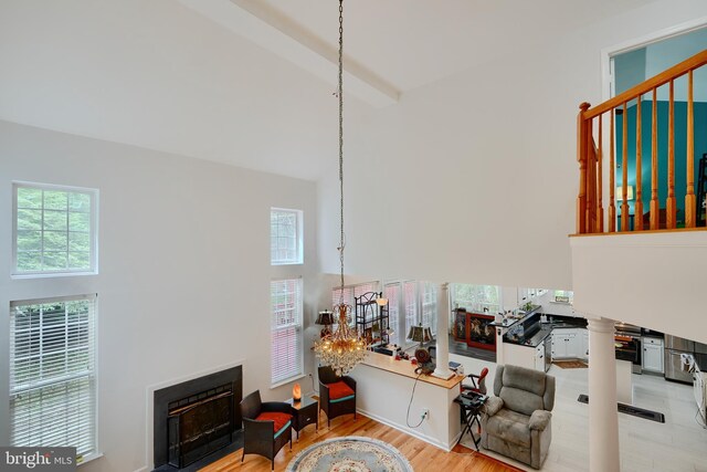 living area with a towering ceiling, a fireplace with flush hearth, and wood finished floors
