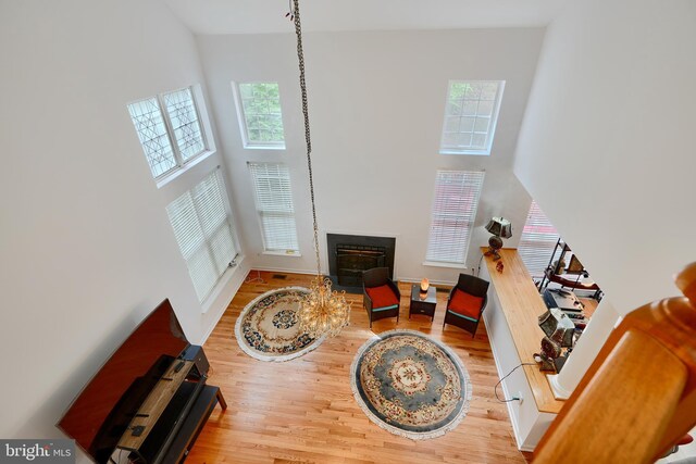 living area featuring a high ceiling, wood finished floors, and a fireplace with flush hearth
