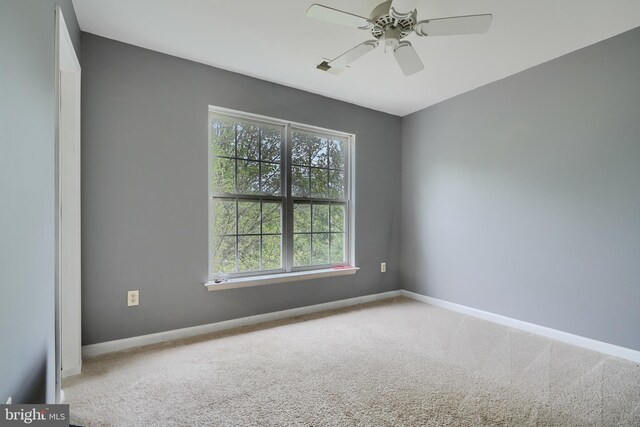 carpeted spare room featuring a ceiling fan and baseboards