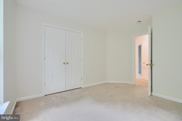 unfurnished bedroom with carpet flooring, baseboards, and a closet